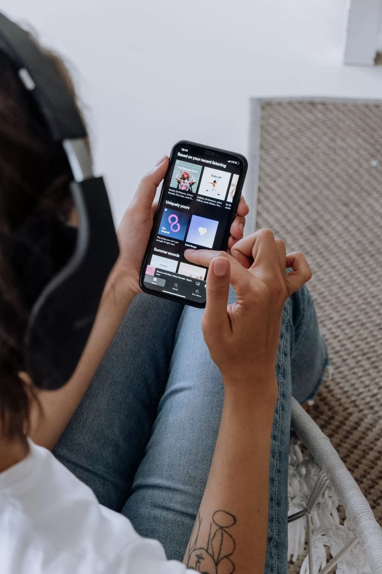 A listener wearing headphones and using Spotify on a smartphone