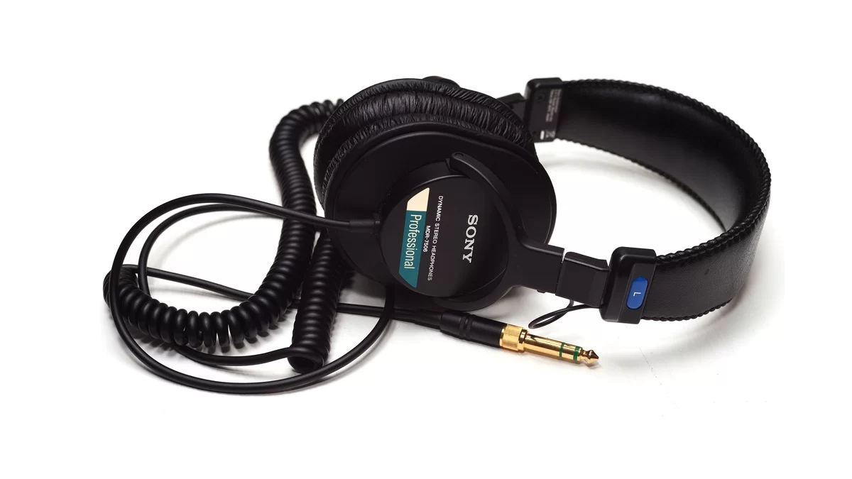 Sony MDR-7506 headphones with their coiled cable and 3.5 mm plug on a white surface