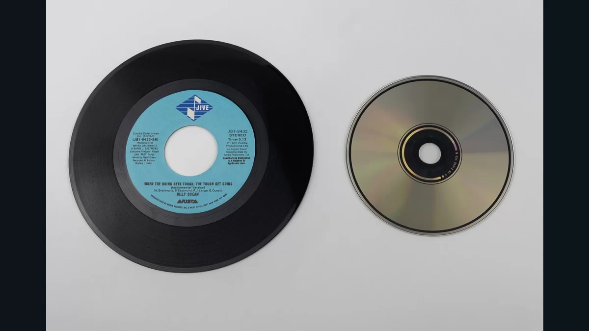 A seven-inch vinyl record beside a compact disc, showing two physical music formats