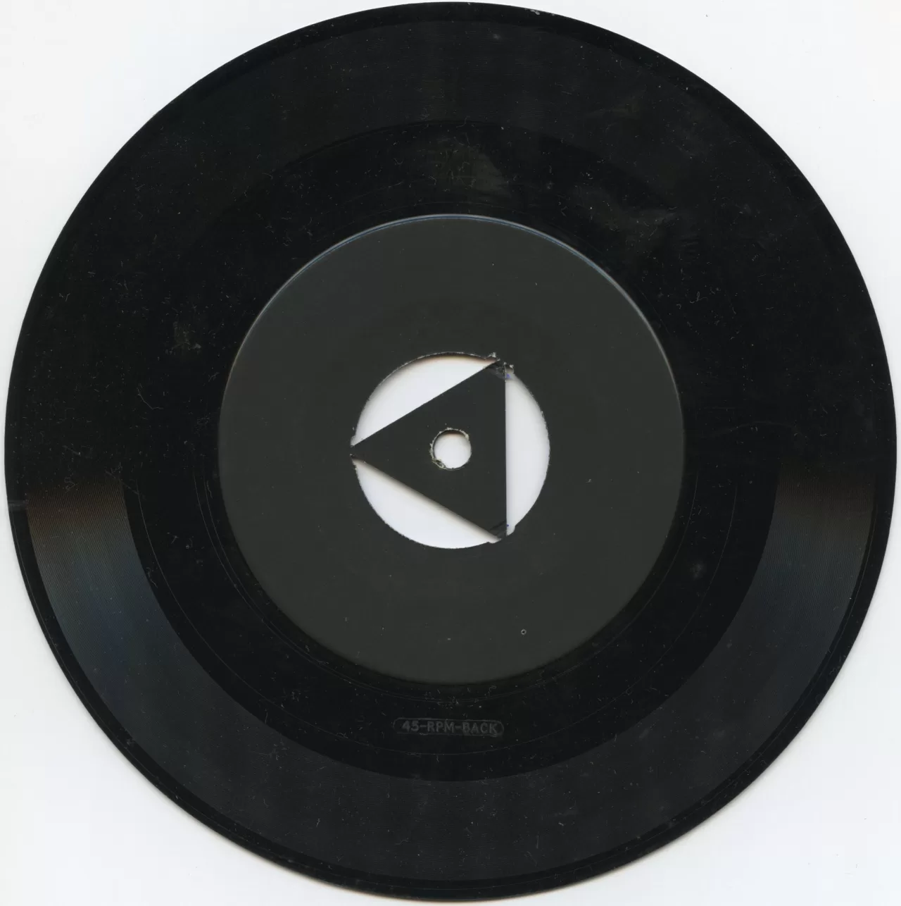 A black seven-inch 45 rpm single with a centre adapter on a white surface